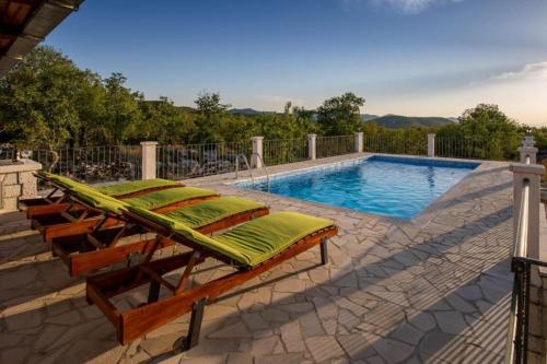 a swimming pool with chaise lounge chairs next to a swimming pool at Villa Menalo in Neum