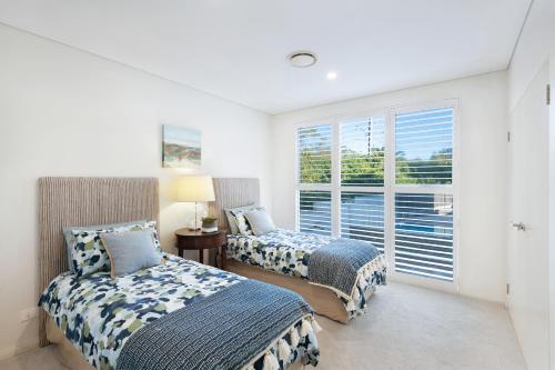 two beds in a room with a window at Kiama Waterfront Apartment in Kiama