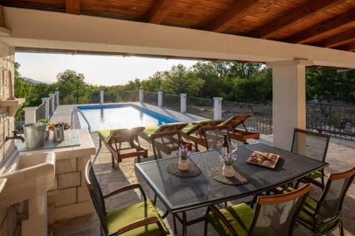 a patio with a table and chairs and a pool at Villa Menalo in Neum