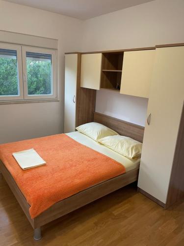 - une chambre avec un lit et une couverture orange dans l'établissement Apartman Lucija Biograd, à Biograd na Moru