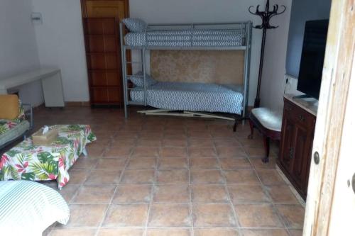 Habitación con suelo de baldosa, cama y TV. en Casa Tena en La Cañada