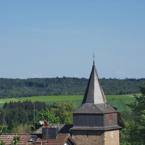 a church with a steeple on top of a building at Wandern, Reiten und die Seele baumeln lassen in Dickschied