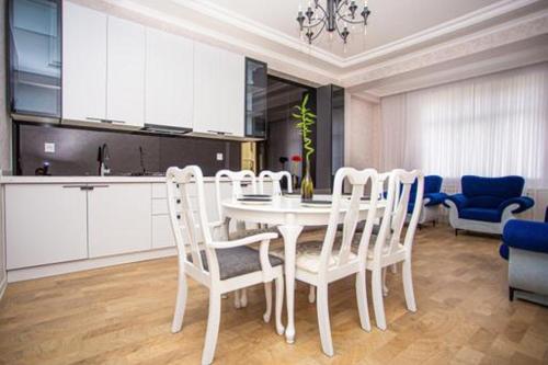 a dining room with a white table and chairs at VIP апартамент in Sumqayyt