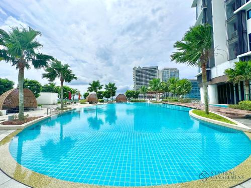 a large blue swimming pool with palm trees and buildings at Almas Suites Puteri Harbour by Stayrene in Nusajaya
