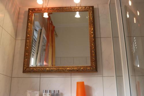 a mirror with a gold frame on a wall at Hotel & Restaurant Pension Bei der Post in Bacharach