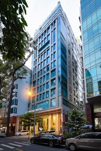 a tall building with cars parked in front of it at Eden Star Saigon Hotel in Ho Chi Minh City