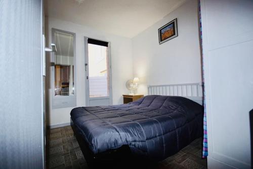 - une chambre avec un lit bleu et une fenêtre dans l'établissement Appartement rez de jardin à 150m de la plage, à Leucate
