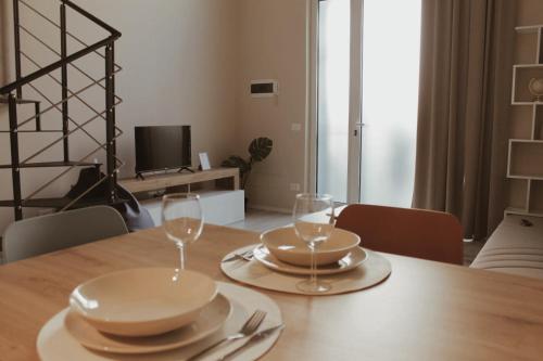 a wooden table with two glasses and plates on it at YR Apartments Milan - Bocconi in Milan