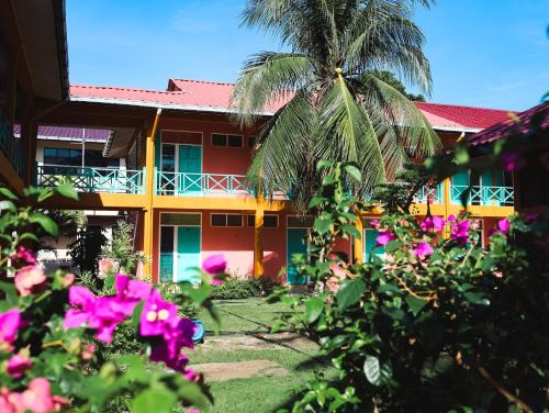 a building with a palm tree and pink flowers at papaya resort in Kampung Tekek