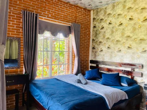 a bedroom with a blue bed with a brick wall at Hoa Son Village Da Lat in Xuan An
