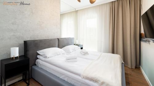 a bedroom with a bed with white sheets and pillows at Wonder Home - Apartamenty Hillside tuż przy stoku, sklep, plac zabaw i zewnętrzna siłownia na terenie kompleksu in Karpacz