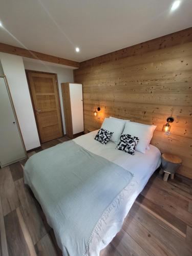 sypialnia z dużym łóżkiem i drewnianymi ścianami w obiekcie Appartement en Chalet 4 étoiles w mieście LʼHuez