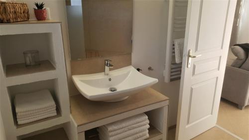 een badkamer met een witte wastafel en een spiegel bij Lou Pic au Loup - Gîte Loup in Cazevieille