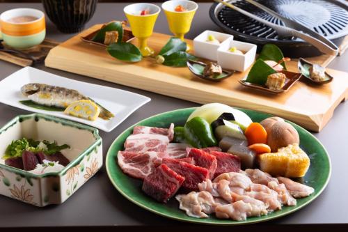 una mesa con un plato de carne y otros alimentos en Hanare no Yado Hanagokoro, en Minamioguni