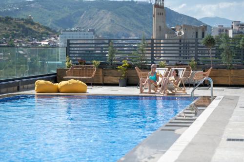 two girls sitting in chairs next to a swimming pool at Royal Tulip Hotel & Casino, Tbilisi in Tbilisi City