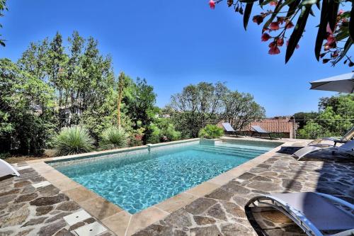 - une piscine avec une passerelle en pierre menant à une maison dans l'établissement Vue mer, Piscine - Appartement Cosy Place, à Bormes-les-Mimosas