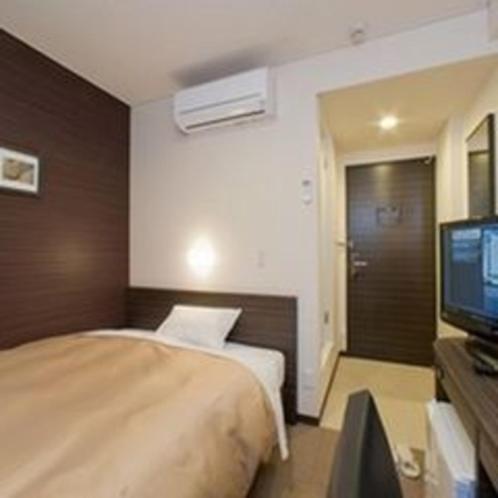 a hotel room with a bed and a television at Smile Hotel Kokura in Kitakyushu
