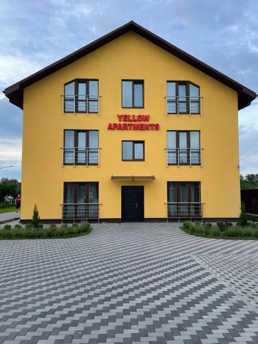 a yellow building with a red sign on it at Yellow apartments in Boryspilʼ