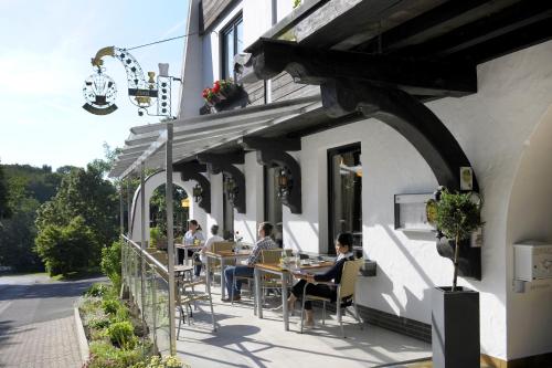 a group of people sitting at tables on a patio at Hotel Bergschlößchen in Simmern