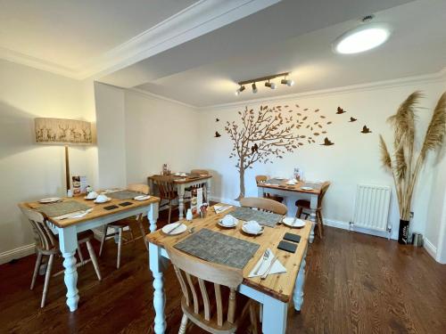 een eetkamer met houten tafels en een boom aan de muur bij Bojangles Guest House in Gretna Green