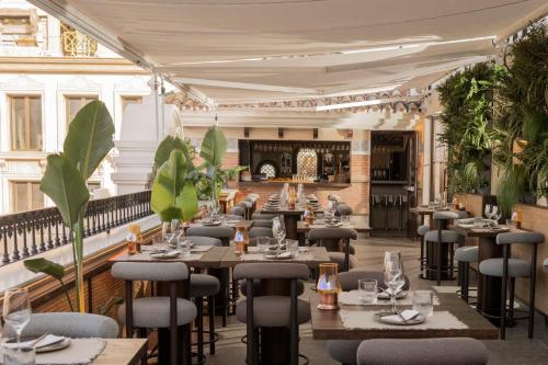 ein Restaurant mit Tischen, Stühlen und Pflanzen in der Unterkunft Hotel El Pilar Andalucia in Estepona