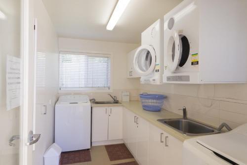 a white kitchen with a sink and a dishwasher at Port Campbell Parkview Motel & Apartments in Port Campbell