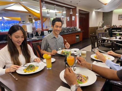 Un gruppo di persone seduti intorno a un tavolo che mangiano cibo di Berjaya Penang Hotel a George Town