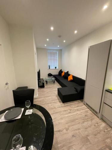 een woonkamer met een zwarte bank en een tafel bij 1 bed apartment in the heart of Staines town centre in Staines upon Thames