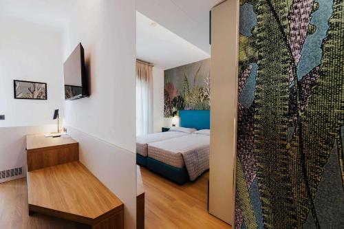 a bedroom with a bed and a wall with a tapestry at Hotel La Serena in Bibione