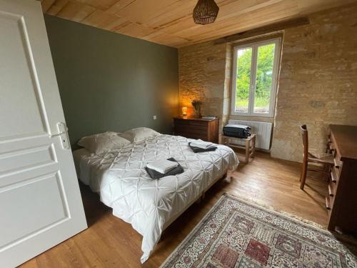Schlafzimmer mit einem Bett, einem Schreibtisch und einem Fenster in der Unterkunft Pépite en Périgord 10-12 couchages, piscine chauffée, rénovée par architecte in Bouzic