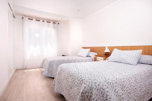 een slaapkamer met 2 bedden en een raam bij MyHouseSpain - Precioso piso cerca de la playa in Gijón