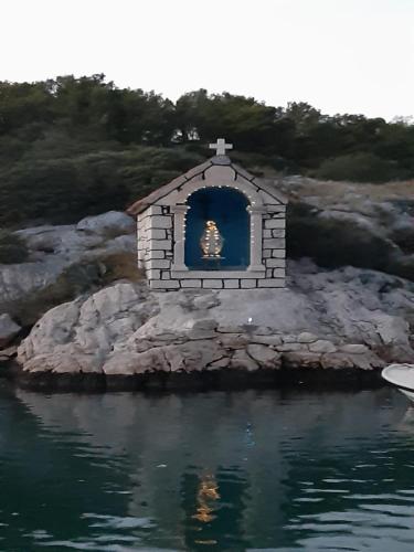 a small chapel on a rocky island in the water at Apartman Luka in Jadrtovac