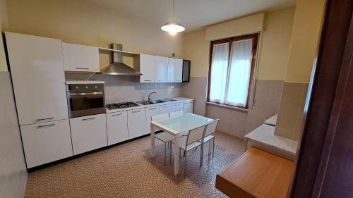 eine Küche mit weißen Schränken, einem Tisch und einem Fenster in der Unterkunft Da Olga e Giubbino - Terrossola in Bibbiena