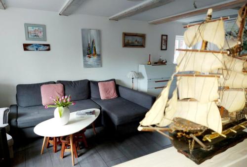 ein Wohnzimmer mit einem schwarzen Sofa und einem Segelboot in der Unterkunft Hochwertiges Fischerhus mit Terrasse und Grill in Greifswald