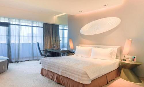 a bedroom with a bed and a desk in a room at Le Meridien Qingdao West Coast in Huangdao