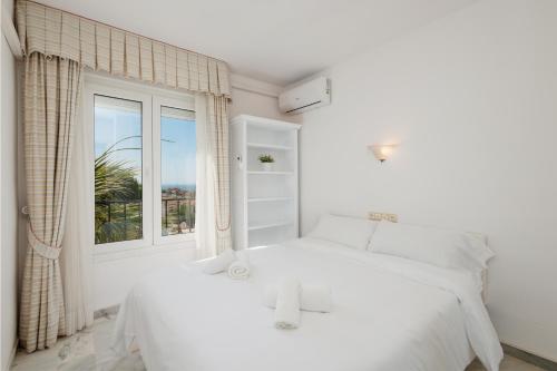 Apartment, close to the beach and sea views, in Marbella في مربلة: غرفة نوم بيضاء بها سرير ونافذة