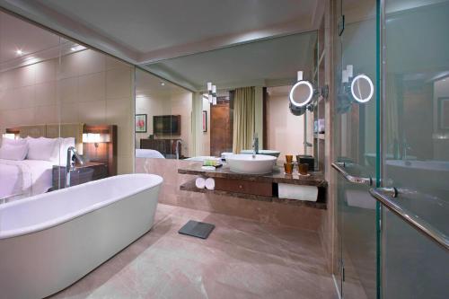 baño con bañera, cama y lavamanos en The Westin Pune Koregaon Park, en Pune