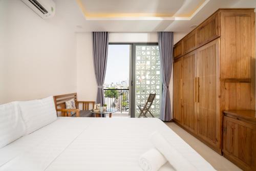 um quarto com uma grande cama branca e uma varanda em Carol Homestay & Apartment Đà Nẵng 4 em Da Nang