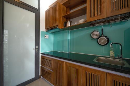 uma cozinha com uma bancada verde e armários de madeira em Carol Homestay & Apartment Đà Nẵng 4 em Da Nang