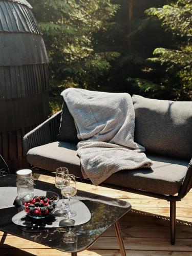 a couch on a patio with a table and wine glasses at Pedaspä Igloo House and Sauna in Pedaspea