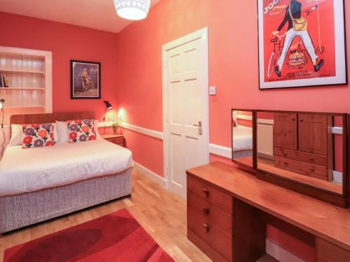 a bedroom with red walls and a bed and a mirror at East Wing in Strathpeffer