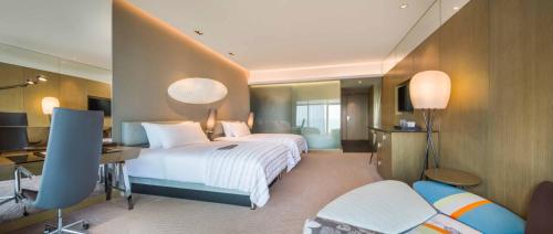 a hotel room with two beds and a desk at Le Meridien Qingdao West Coast in Huangdao