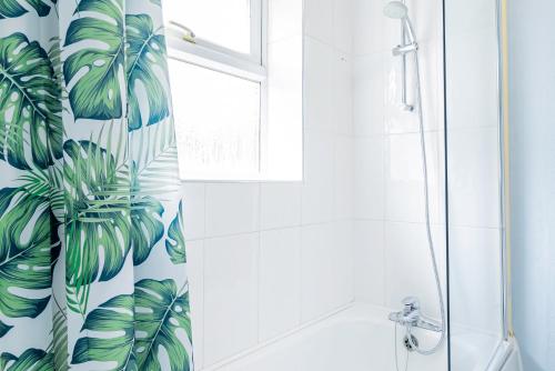 a bathroom with a shower curtain with green leaves at Central MK Parking Garden Contractor Families in Milton Keynes