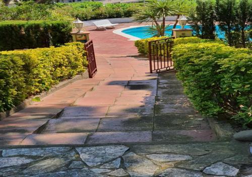 a stone walkway next to a pool with bushes at Apartamento Vacacional en Platja D'Aro in S'agaro