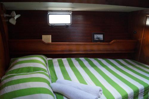 um quarto com uma cama com riscas verdes e brancas e uma janela em Voilier Birdie em Lorient