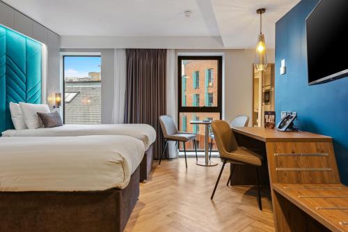 a hotel room with two beds and a desk at Roomzzz Newcastle City in Newcastle upon Tyne