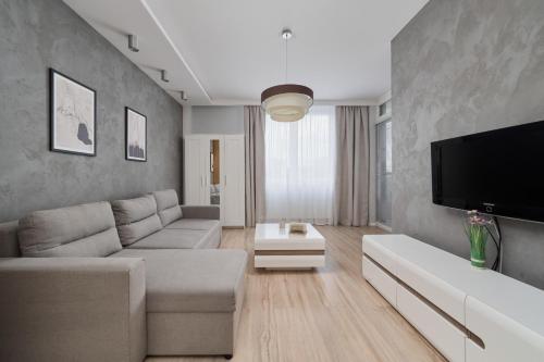 a living room with a couch and a flat screen tv at Modern Studio with Balcony for 4 Guests in Wrocław by Renters in Wrocław