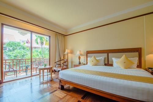 um quarto com uma cama grande e uma varanda em Sokha Angkor Resort em Siem Reap