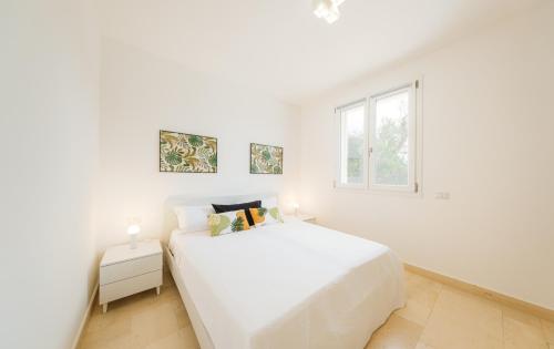 - une chambre blanche avec un lit blanc et une fenêtre dans l'établissement HelloApulia La Perla di Torre Guaceto, à Serranova