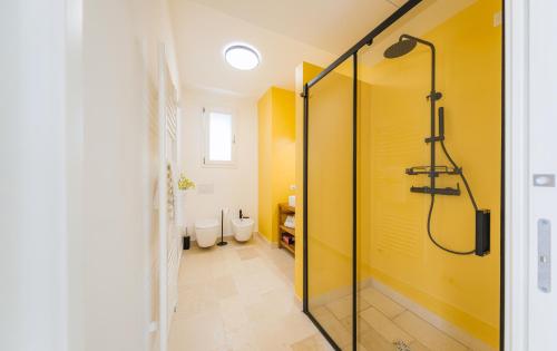 La salle de bains est pourvue d'une douche et d'un mur jaune. dans l'établissement HelloApulia La Perla di Torre Guaceto, à Serranova